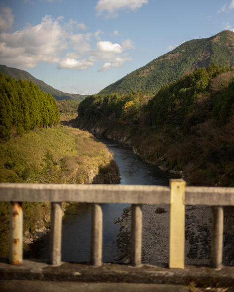 Looking out over Funaki Bridge back north up Miya River, blue skies, warm light.