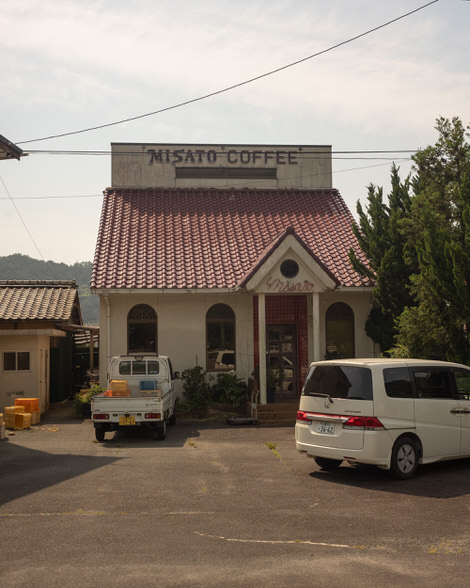 Mistaos cofee, little kissaten with two white vehicles outside.