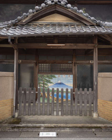 The entrance to a closed down city sento, or public bath, a tiled Mount Fuji on the entrance with the words: matsu no yu
